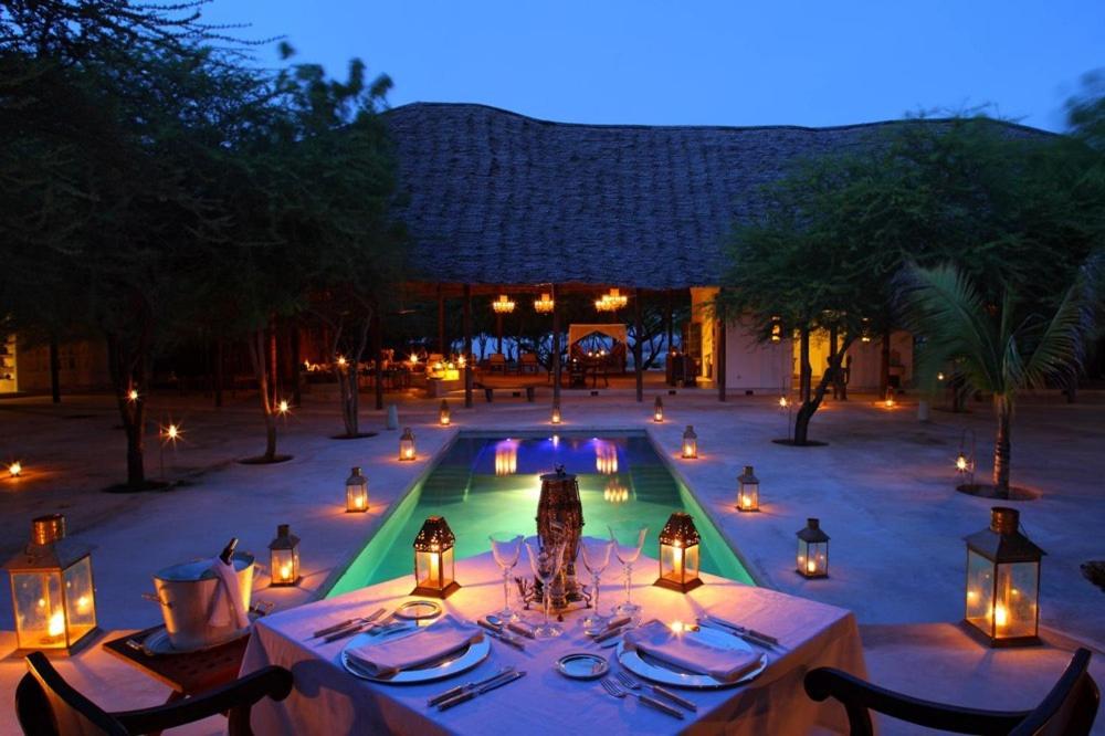 a table with candles in front of a pool at night at The Red Pepper House in Lamu