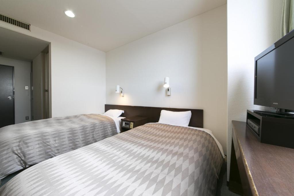 a hotel room with two beds and a flat screen tv at Okadaya Bayside / Vacation STAY 72735 in Toyohashi