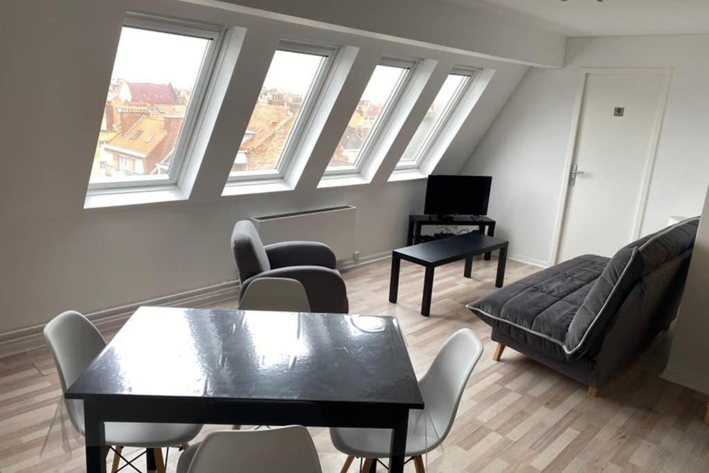 un soggiorno con divano, tavolo e finestre di Appartement 300m Plage a Dunkerque