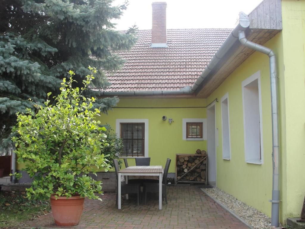 una pequeña casa amarilla con mesa y sillas en Zanati Apartmannház, en Nagykapornak