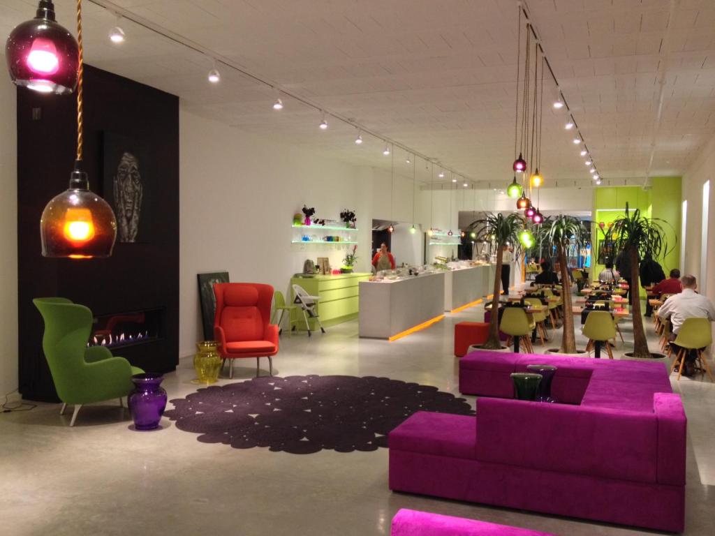 a living room with a purple couch and colorful chairs at Hotel Corbie Geel in Geel