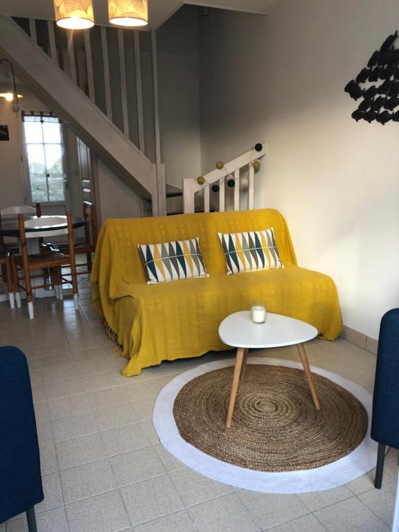 a living room with a yellow couch and a table at Maison Bord de Mer LE BIGORNEAU l'Herbaudière in Noirmoutier-en-l'lle