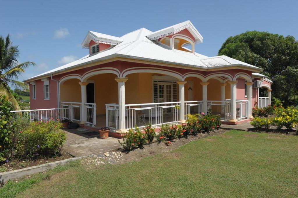a pink and yellow house with flowers in the yard at Villa Yona in Sainte-Anne
