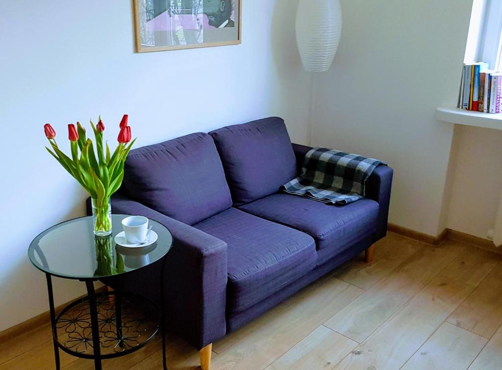 a purple couch in a living room with a table at Rynek Staromiejski Apartment in Koszalin