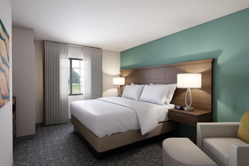 a bedroom with a large white bed and a chair at Staybridge Suites - Columbus - Worthington, an IHG Hotel in Worthington