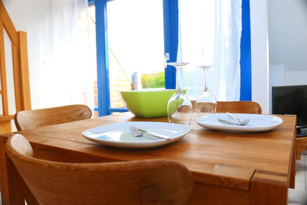 een houten tafel met twee witte borden en een groene kom bij Nordseepier in Horumersiel
