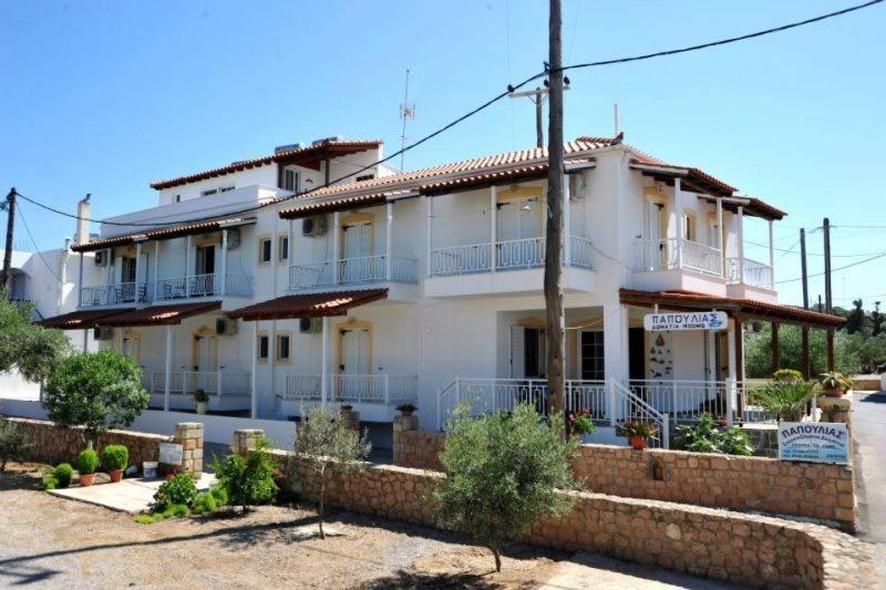 ein großes weißes Haus mit Ziegelwand in der Unterkunft Papoulias Rooms in Elafonisos