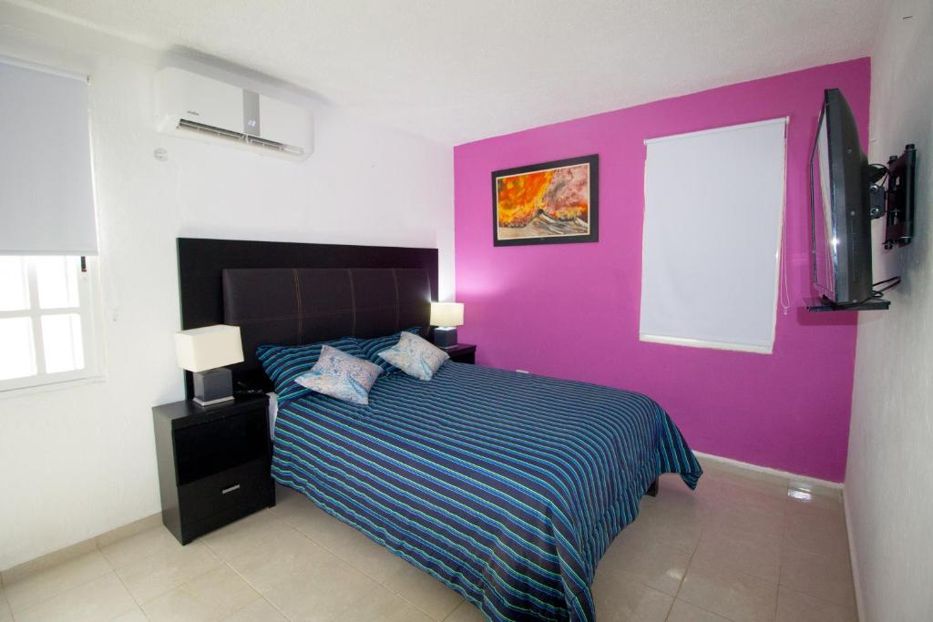 ein Schlafzimmer mit einem Bett mit einer lila Wand in der Unterkunft Casa Zac Nicte Mx-Habitacion IXCHEL in Cancún