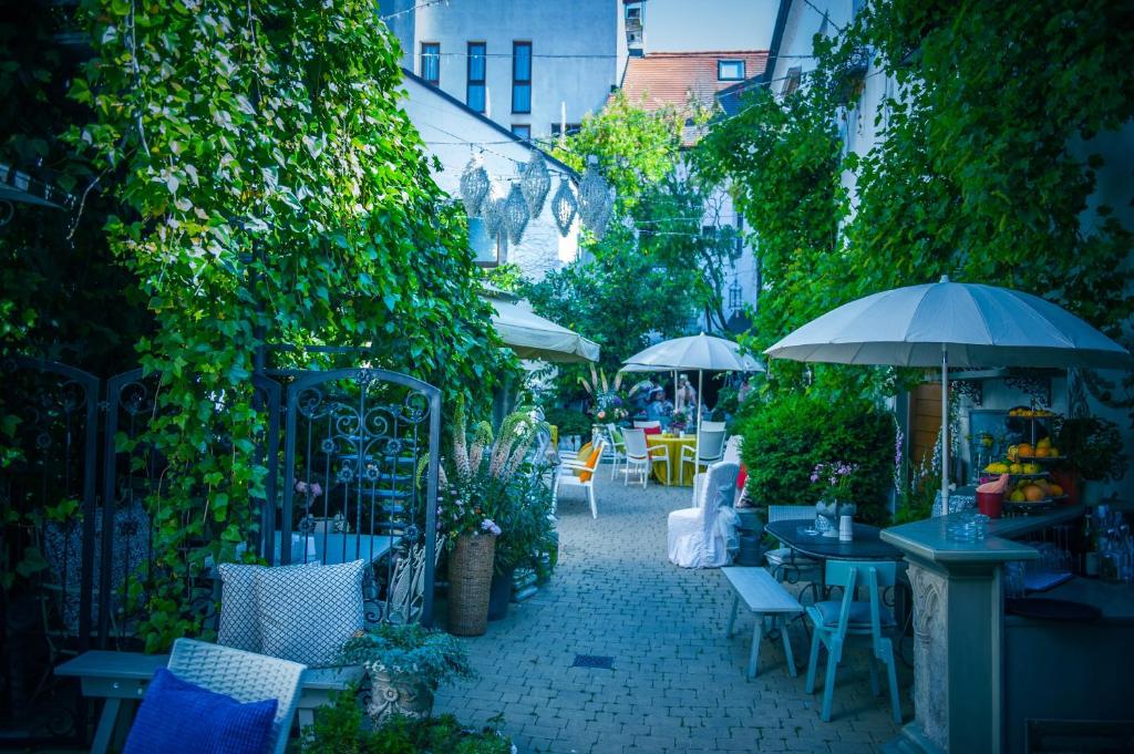 un patio al aire libre con mesas, sillas y sombrillas en Art Boutique Hotel Bürgerhaus, en Rust