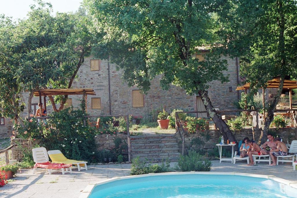 uma piscina num quintal com pessoas sentadas em cadeiras em Agriturismo La Fagianaia em Borgo a Buggiano