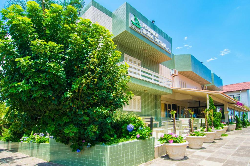 a green building with a tree in front of it at Pousada Brisa do Mar in Torres