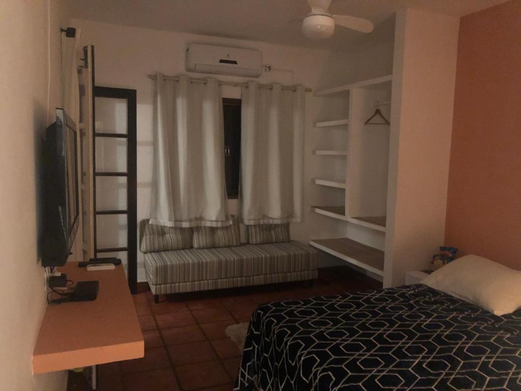 1 dormitorio con 1 cama y una ventana con cortinas en Pousada Kai en Itanhaém