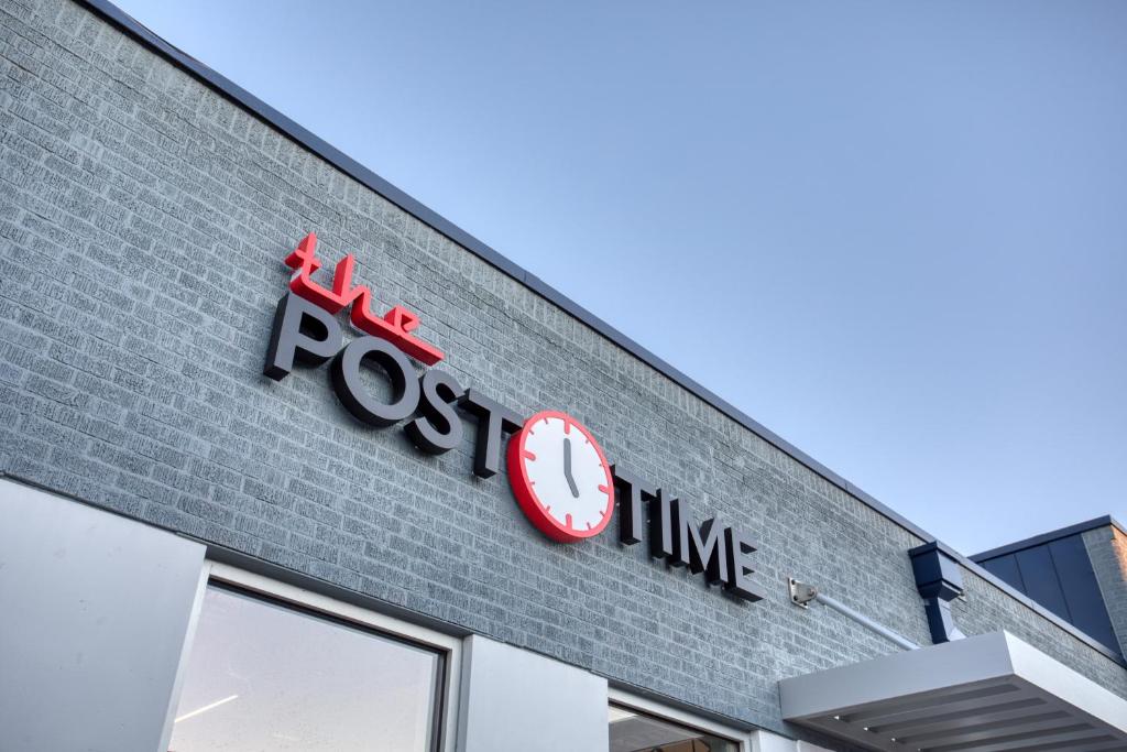 un orologio rosso sul lato di un negozio di Post Time Inn a Carlsbad