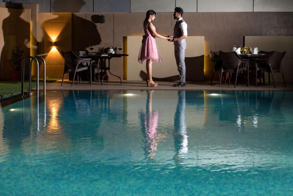 a man and woman standing next to a swimming pool at Radisson Udaipur in Udaipur