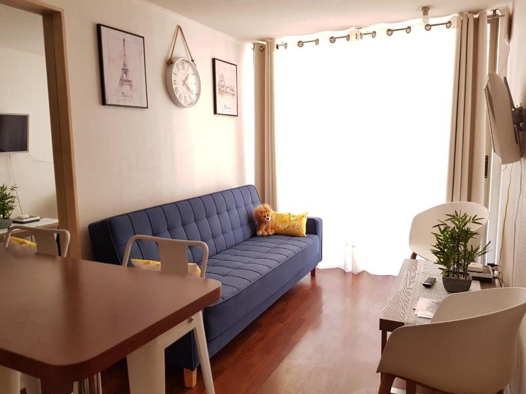 sala de estar con sofá azul y mesa en Departamento A Pasos de Metro Ñuble, en Santiago