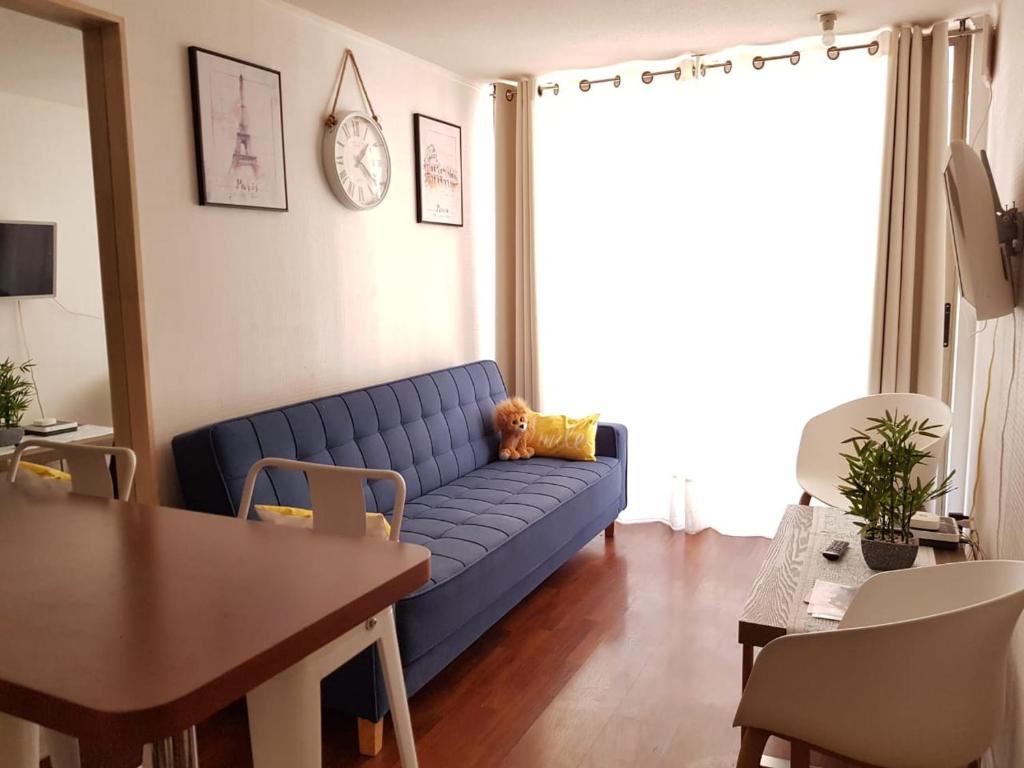 a living room with a blue couch and a table at Departamento A Pasos de Metro Ñuble in Santiago