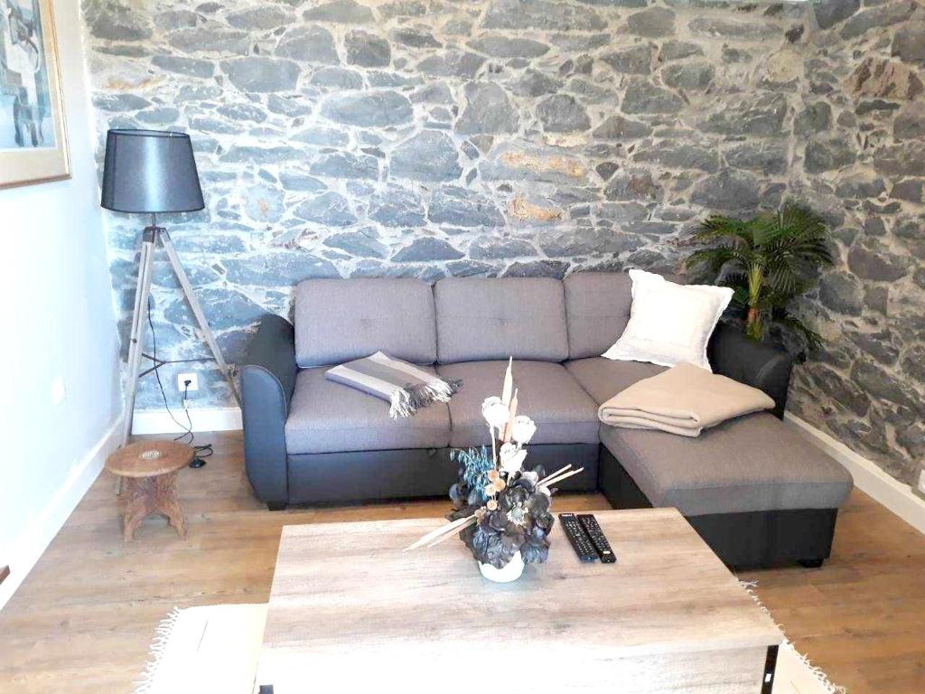 a living room with a couch and a stone wall at One bedroom house with sea view and wifi at Calheta in Calheta