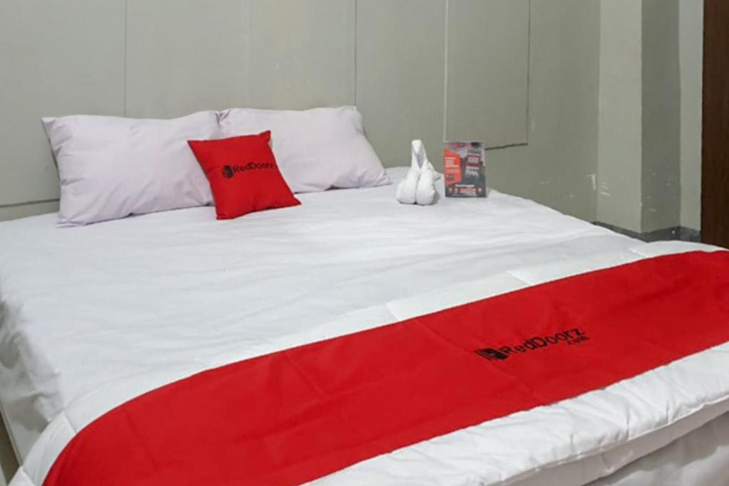 a red and white bed with red pillows on it at RedDoorz @ Hotel Yaki Mamuju in Rimuku