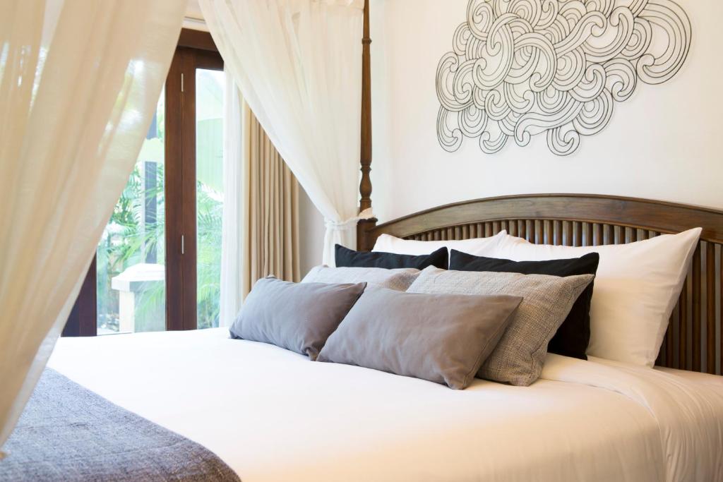 a bedroom with a white bed with a chandelier at Tolani Southgate Villa Chiang Mai in Chiang Mai