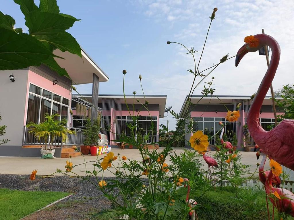 een flamingo voor een gebouw met bloemen bij บ้านสวนนิสา in Sattahip