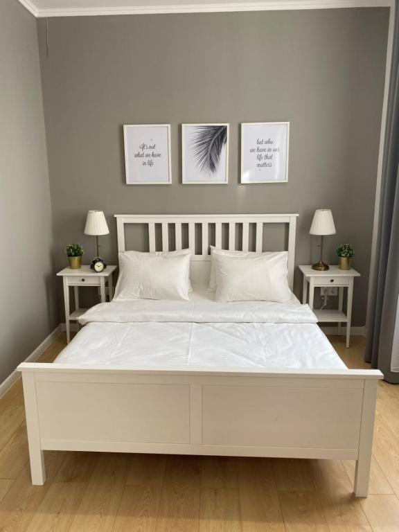 ein weißes Bett in einem Schlafzimmer mit drei Bildern an der Wand in der Unterkunft Zarya Lux Hotel in Prokop'yevsk