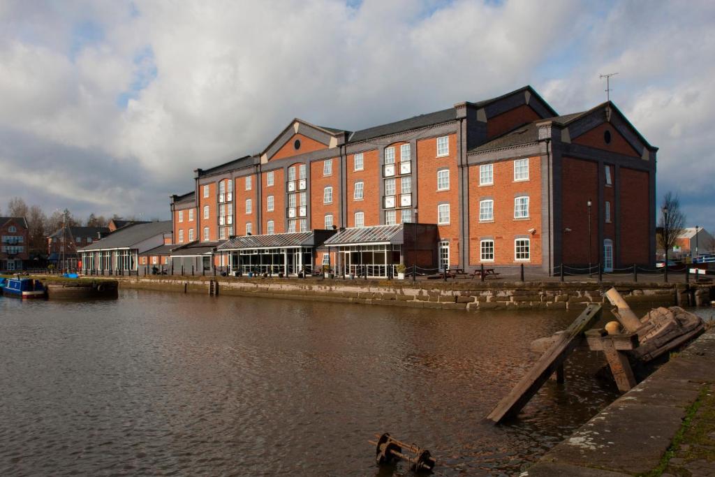 a large brick building next to a body of water at Holiday Inn Ellesmere Port/Cheshire Oaks, an IHG Hotel in Ellesmere Port