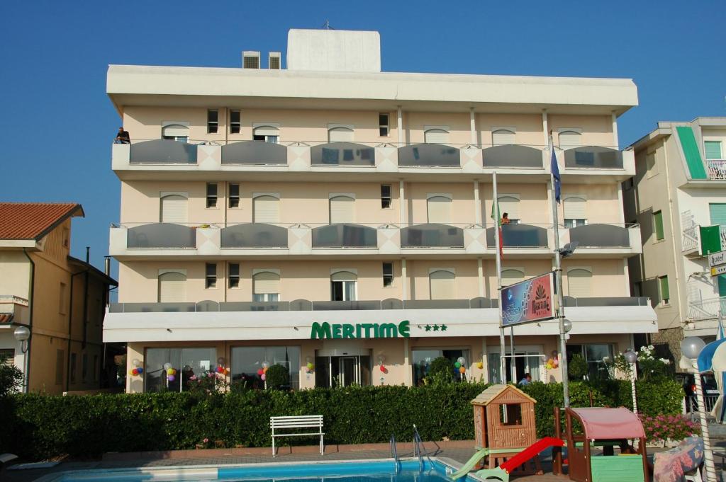 een groot gebouw met een zwembad ervoor bij Hotel Meritime in Bellaria-Igea Marina