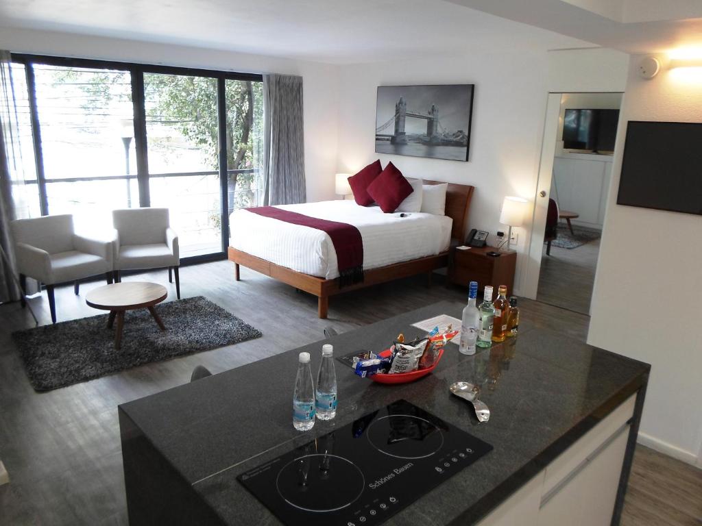 a hotel room with a bed, table and refrigerator at Armonik Suites in Mexico City
