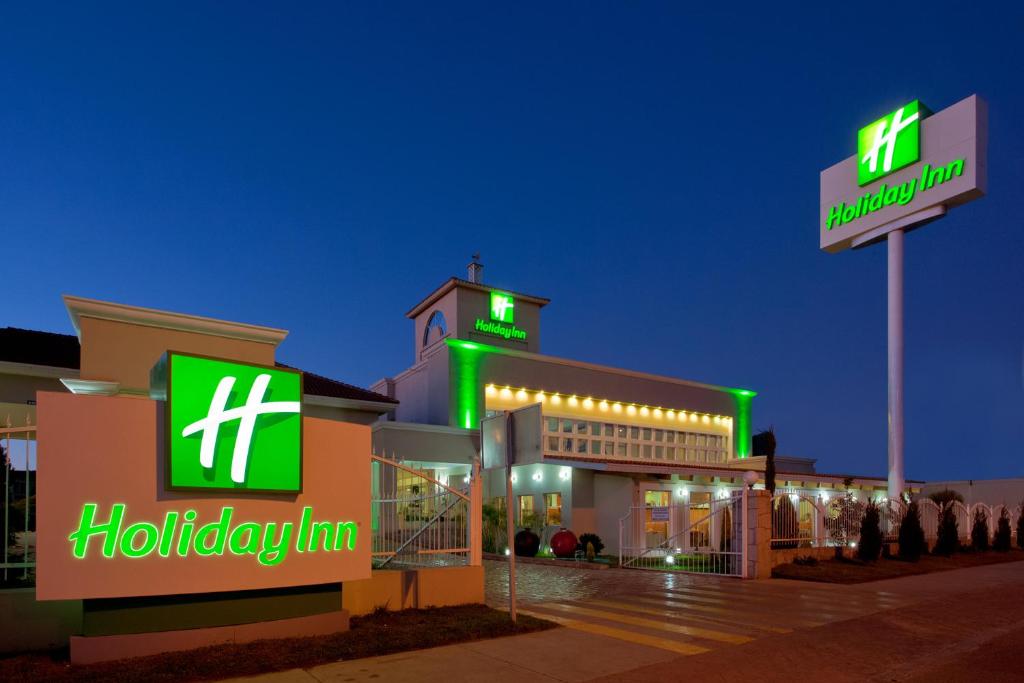Holiday Inn Durango, an IHG Hotel في ولاية دورانغو: مستشفى به لوحات نيون خضراء على مبنى
