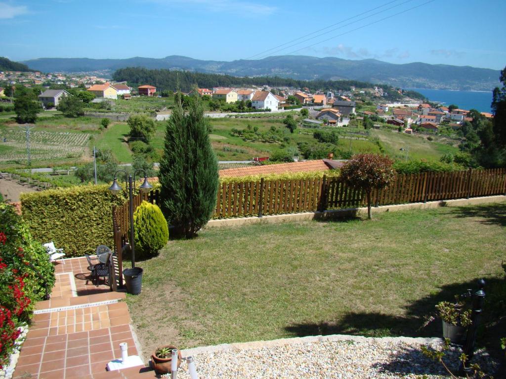 a garden with a fence and a view of a town at Hotel Rural Seixalvo in Sanxenxo