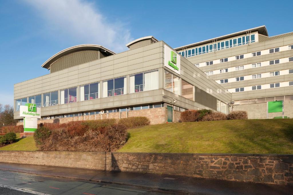 a large building with a grassy hill in front of it at Holiday Inn Edinburgh Zoo, an IHG Hotel in Edinburgh