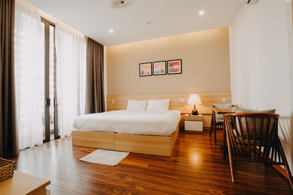 a bedroom with a bed and a table with a chair at Soleil House in Hue