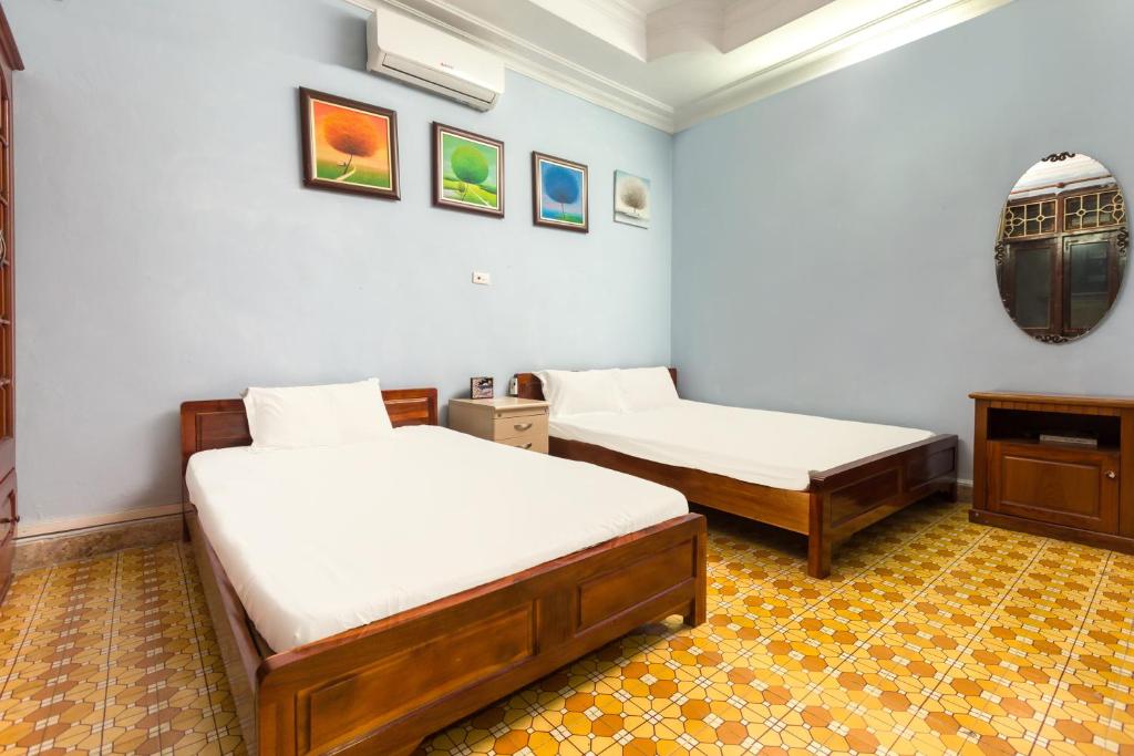 a bedroom with two beds and a mirror on the wall at OYO 619 Chikoo Homestay spot-on in Hanoi