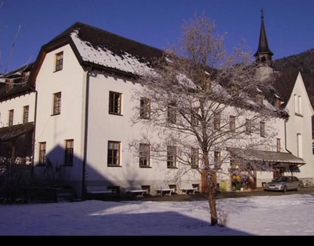 un gran edificio blanco con un árbol en la nieve en Seminar- und Gästehaus im Kloster Bezau, en Bezau