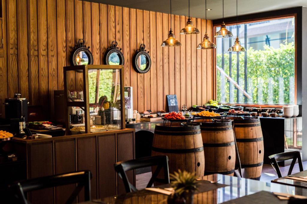 a restaurant with wooden walls and barrels and a bar at Aurico Kata Resort & Spa - SHA Extra Plus in Kata Beach