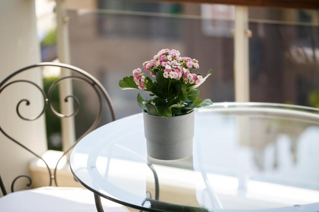 a vase of pink flowers sitting on a glass table at Melon Suites in Thessaloniki