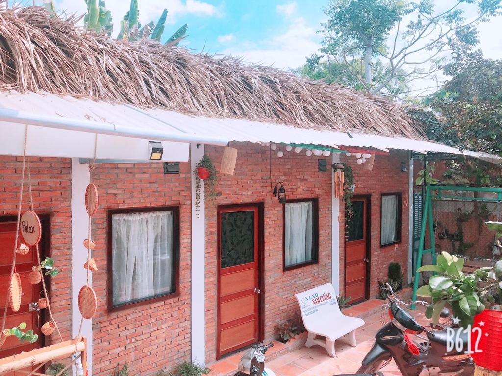 ein Backsteinhaus mit roten Türen und einem Stuhl in der Unterkunft Green Sunshine in Cần Thơ