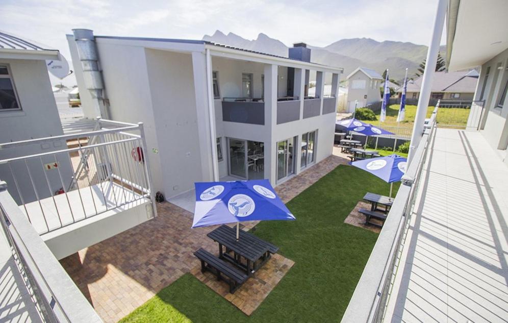 a balcony of a house with a yard with blue umbrellas at Kleinmond Lodge in Kleinmond