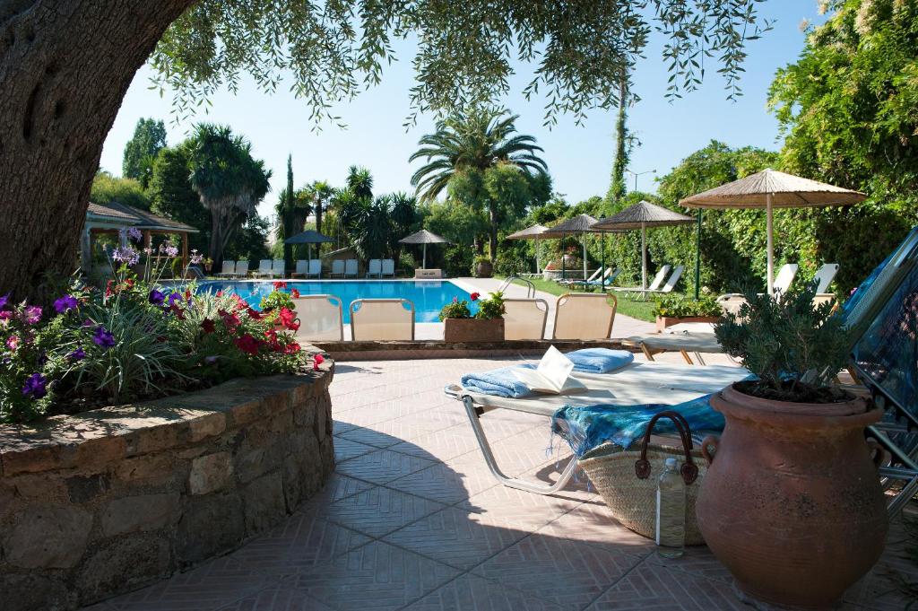 un patio con tavolo, sedie e piscina di Spiti Prifti Apartments a Gouviá