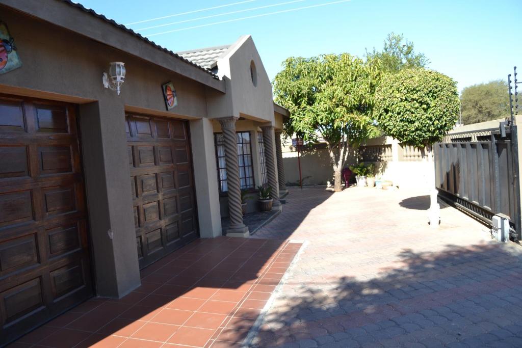 a house with two garage doors and a sidewalk at Triple Palms Bed and Breakfast in Gaborone
