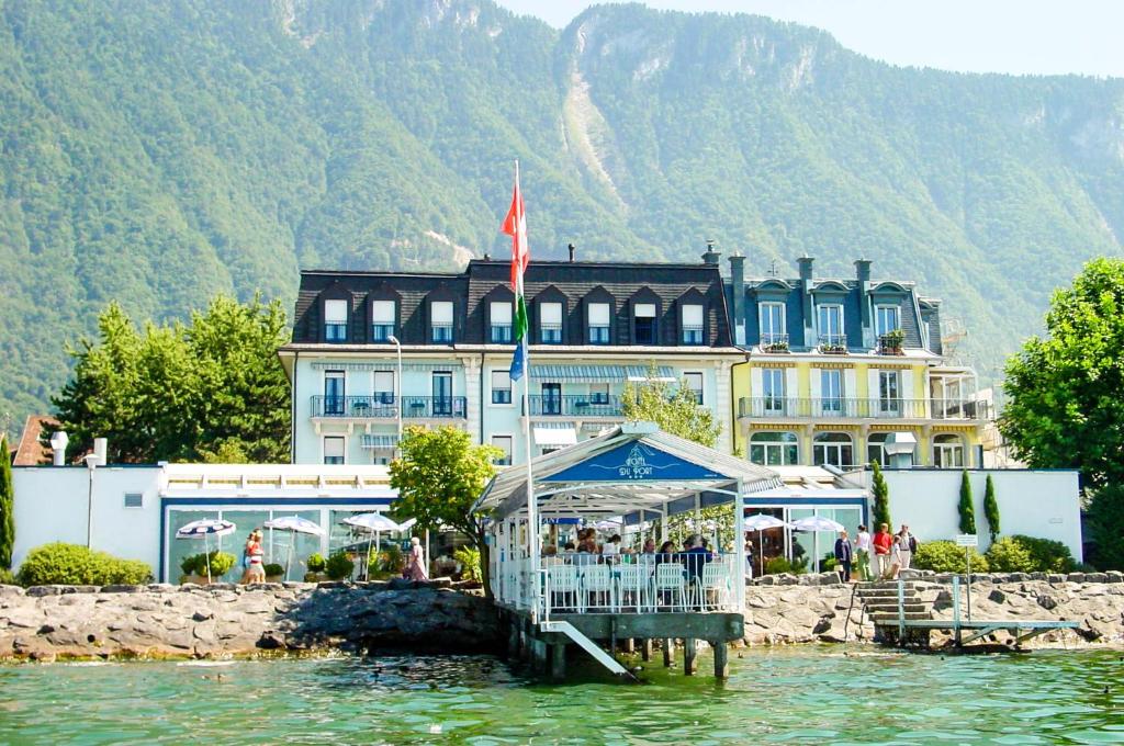 ein Gebäude auf dem Wasser mit einem Zelt davor in der Unterkunft Hôtel du Port in Villeneuve