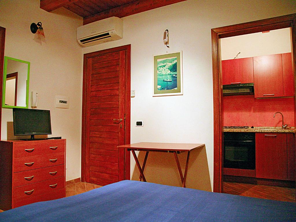 ein Schlafzimmer mit einem Bett und einem Tisch sowie eine Küche in der Unterkunft CASA BRICIOLE 1 e 2 in Scilla