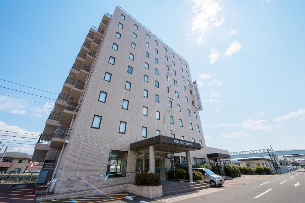 Pacific Hotel Shiroishi في Shiroishi: مبنى طويل وبه سيارة متوقفة أمامه