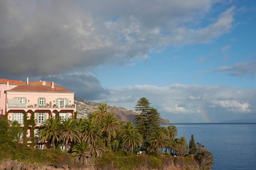 a house on top of a hill next to the water at Reid's Palace, A Belmond Hotel, Madeira in Funchal