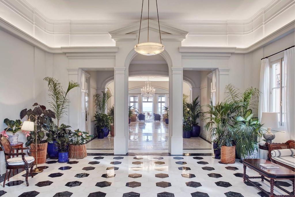 a large room with a lobby with plants and a chandelier at Reid's Palace, A Belmond Hotel, Madeira in Funchal