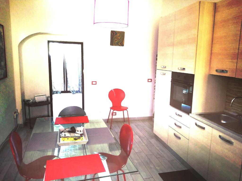 a kitchen with a table and red chairs and a table and a table at Siracusa,tra ortigia e il mare in Siracusa