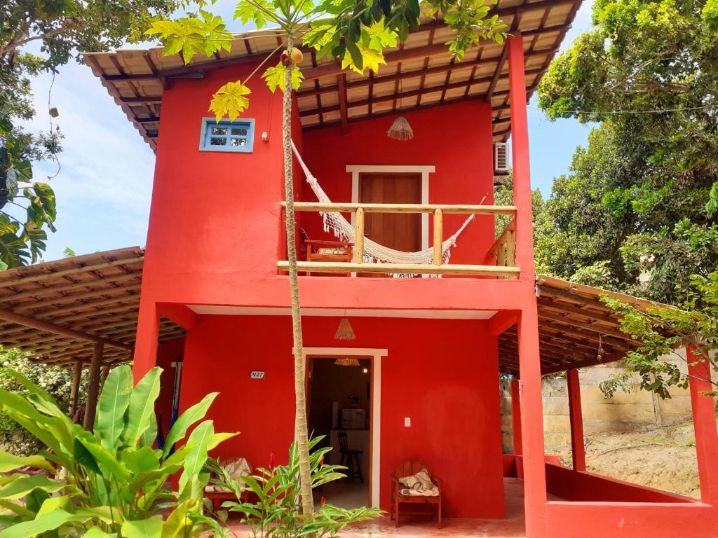 una casa roja con balcón frente a ella en Trancoso, Bahia - Casa por temporada com estacionamento, en Trancoso