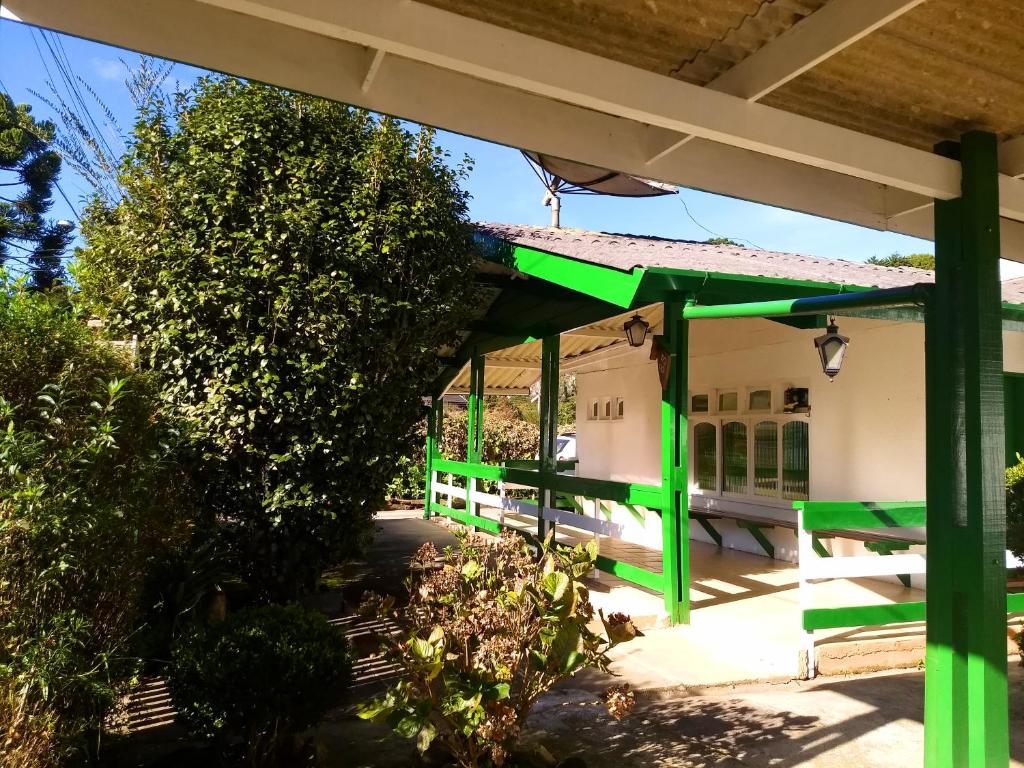 un edificio verde y blanco con porche en Pousada Casa D'Antonia, en Campos do Jordão