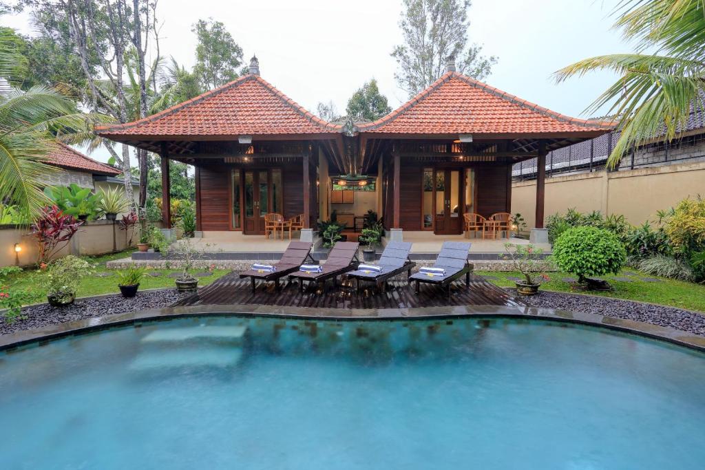 una casa con una piscina con sillas y un edificio en Pondok Chandani Suite, en Tampaksiring