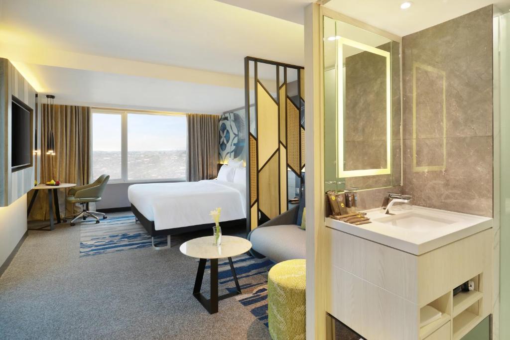 a hotel room with a sink and a bed at Novotel Suites Yogyakarta Malioboro in Yogyakarta